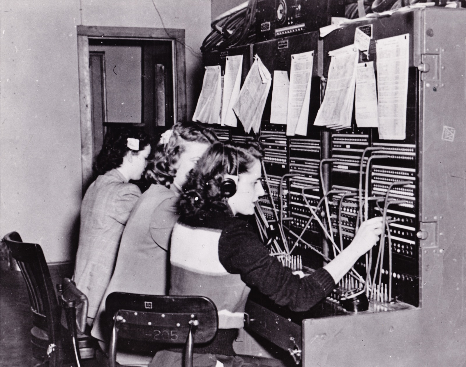 Telephone switchboard operators connecting calls by hand at Fort Richardson, 1950.